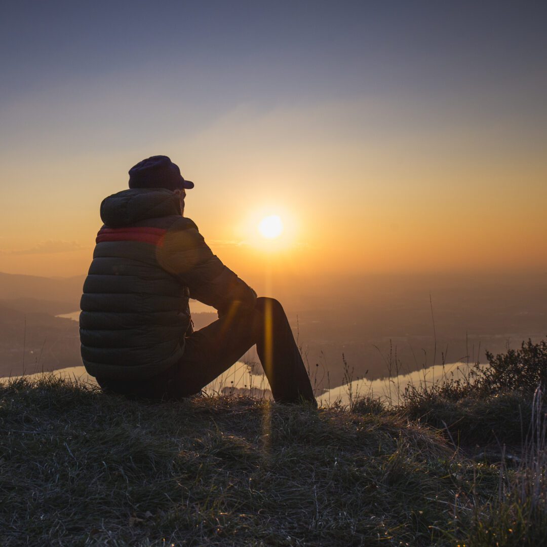 Person watching sunset from a hilltop.